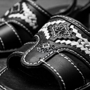 Close-up of black and white leather sandals with detailed stitching.