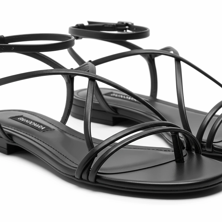 Chic black strappy flat dress sandals with delicate ankle straps, offering a refined look without the heel.